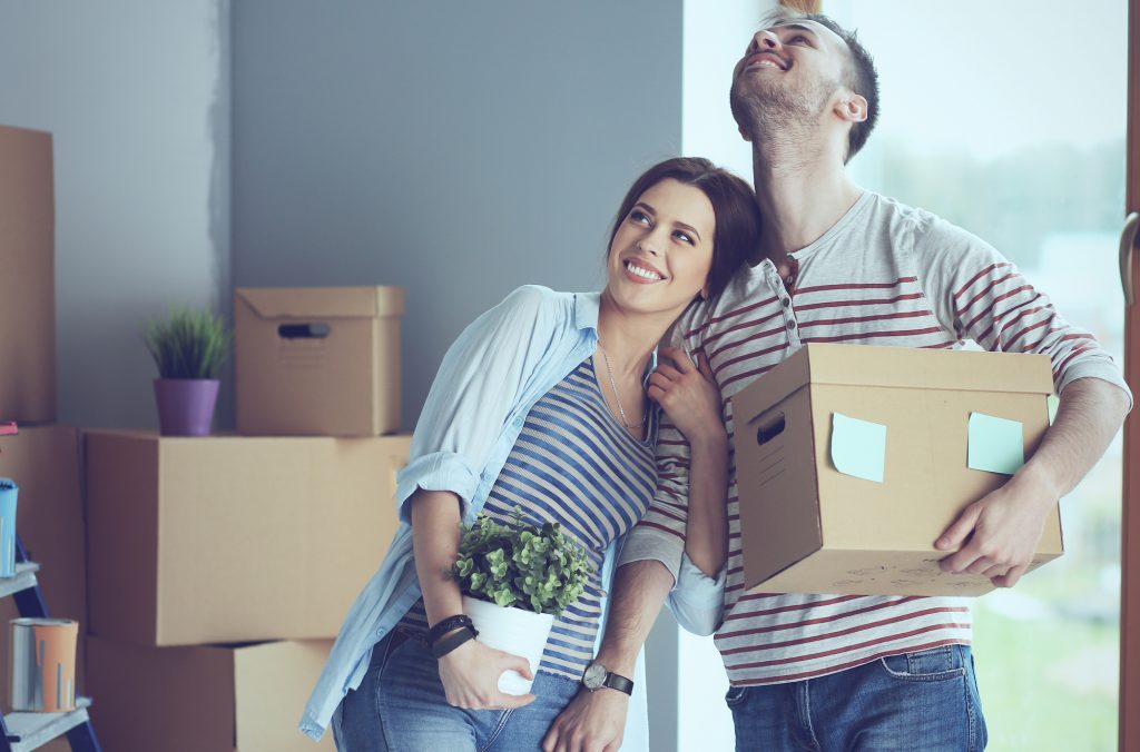 couple moving boxes holding plant