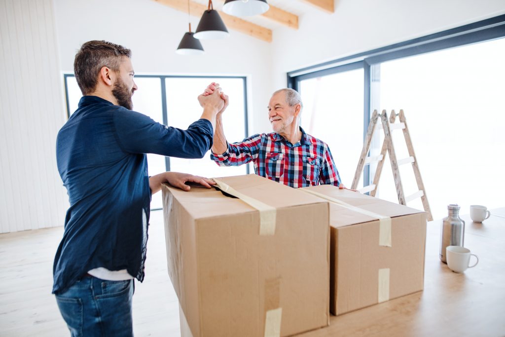 A mature man with his senior father furnishing new house, a new home concept.