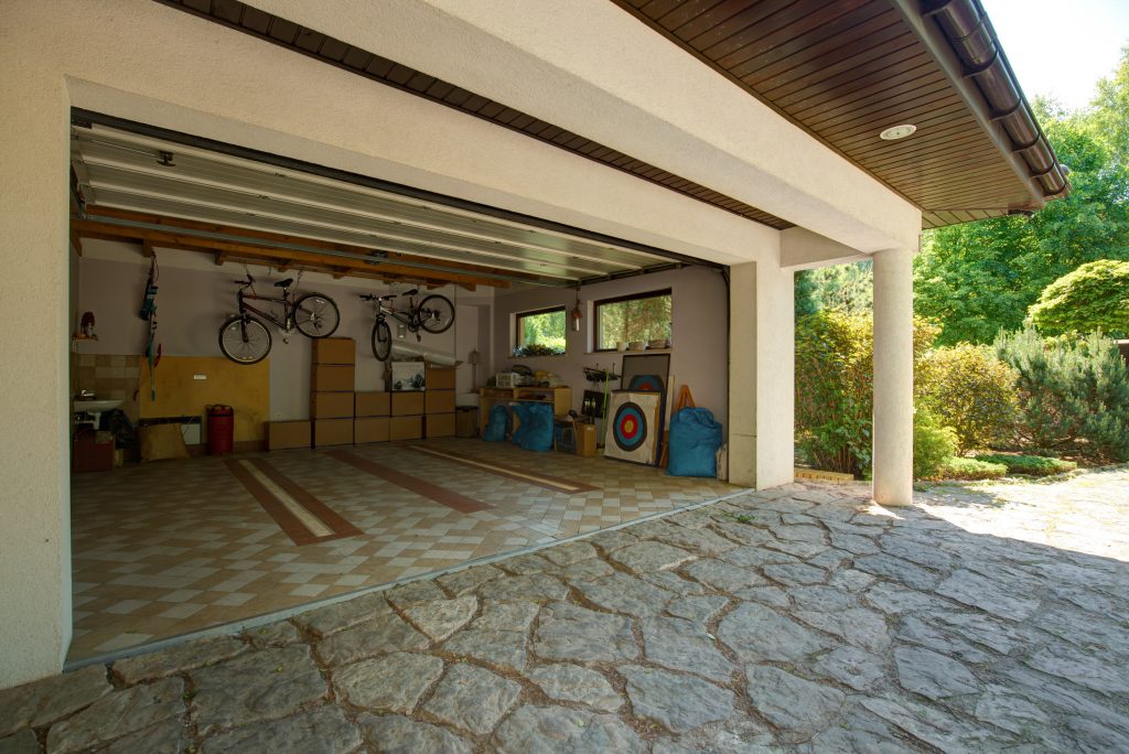 garage with garage door open showing moving boxes stacked neatly on the far wall