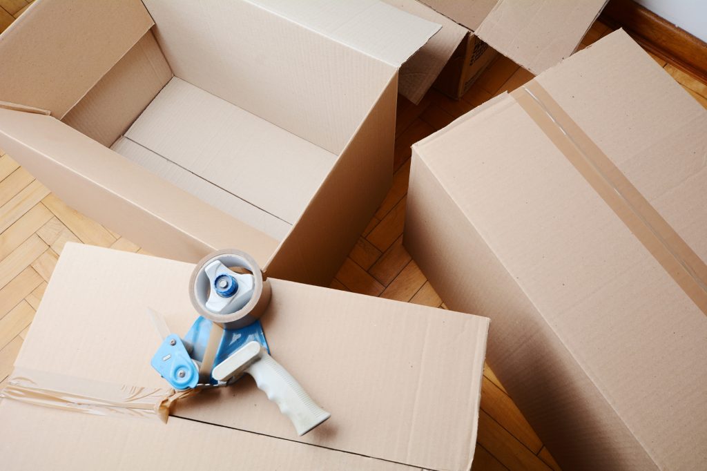 Tape dispenser sealing a shipping cardboard box. Indoors