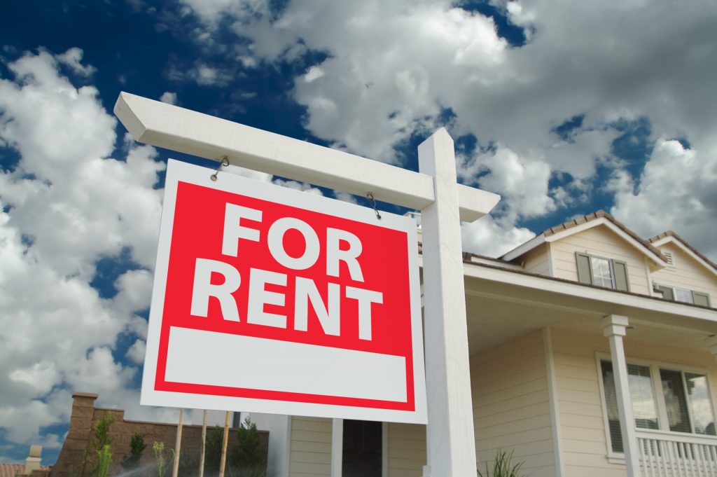 For rent sign in front of new home. dramatic blue sky and clouds behind.