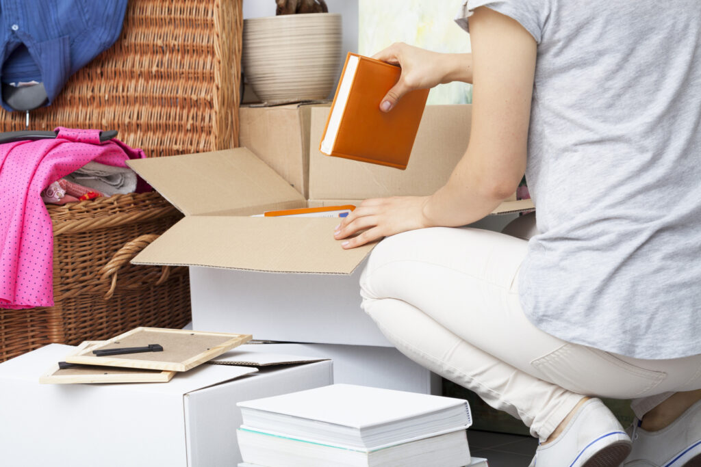 Person squating and loading books into a moving box.