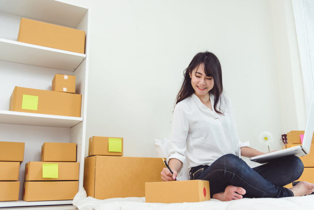 Woman sitting on floor with moving boxes with colorful yellow post-it notes identifying the boxes.